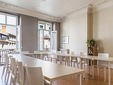 Heller Unterrichtsraum mit großen Fenstern und U-Tisch-Anordnung für Französisch-Sprachkurse in Bordeaux.